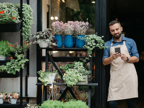 Dueño de tienda revisando su celular frente a su local