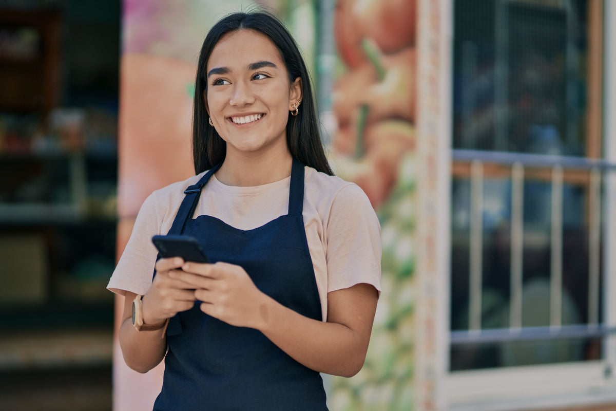 Dueña de un almacén revisando mensajes en su celular